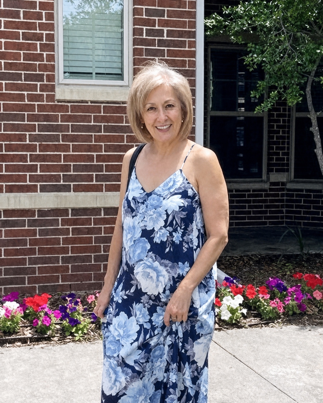 Gulnara Karimova smiling outdoors beside a garden in a blue floral dress.